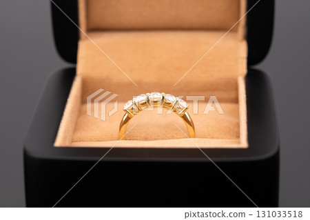 A gold ring with diamonds in it is in a black box 131033518