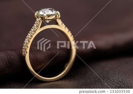 A gold ring with a diamond in the center and a band of diamonds around it 131033530