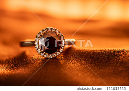 A ring with a diamond and a halo is on a table 131033533