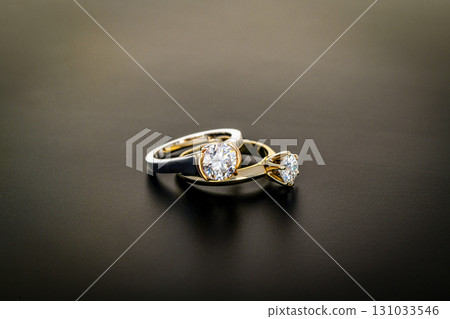 Two rings, one silver and one gold, with a diamond in the middle 131033546