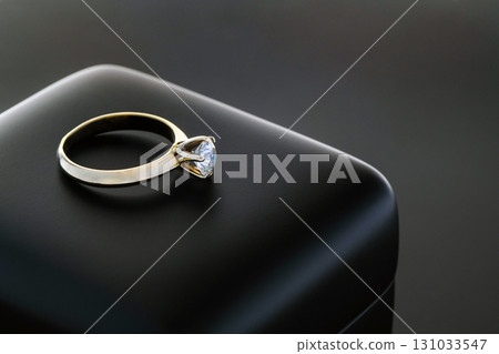 A gold and diamond ring is sitting on a black surface A gold and diamond ring is sitting on a black surface 131033547