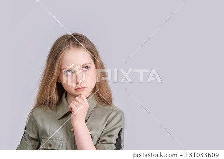 Thoughtful caucasian young girl with freckles pondering against gray background Thoughtful caucasian young girl with freckles pondering against gray background 131033609