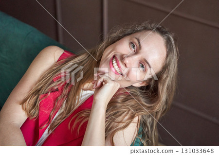 Smiling caucasian young adult female with long hair relaxing indoors in bright Smiling caucasian young adult female with long hair relaxing indoors in bright 131033648
