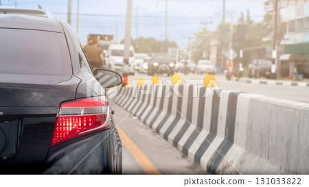 Rear side of black car with turn on brake light. Traffic condition on the road in the hot time of Thailand. Side road with traffic barriers made of concrete. Rear side of black car with turn on brake light. Traffic condition on the road in the hot time of Thailand. Side road with traffic barriers made of concrete. 131033822