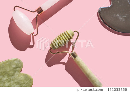 Skincare tools on pink background with jade roller and facial massager Skincare tools on pink background with jade roller and facial massager 131033866
