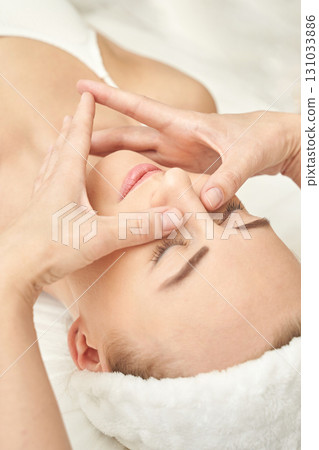 Spa treatment for relaxation: young caucasian female receiving facial massage 131033886