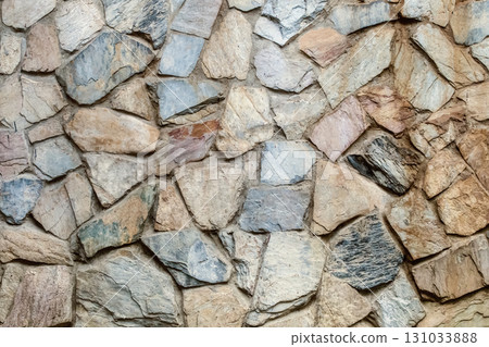 old stone fence made of gray and brown cobblestones, uneven stones close up 131033888