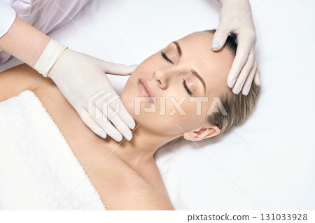 Caucasian adult female relaxing during spa facial treatment with therapist Caucasian adult female relaxing during spa facial treatment with therapist 131033928