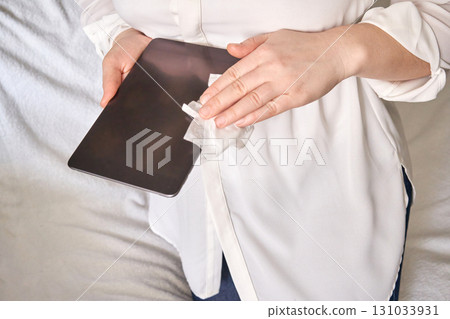 Asian female adult cleaning tablet surface with wipe for hygienic device Asian female adult cleaning tablet surface with wipe for hygienic device 131033931