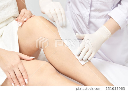 Female adult hair removal procedure in spa setting with wax strip application Female adult hair removal procedure in spa setting with wax strip application 131033963