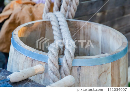oak barrel with iron rings, light barrel and rope close-up 131034007