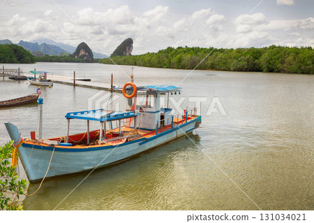 thailand fishing boat moored on river pier against tropical forest background thailand fishing boat moored on river pier against tropical forest background 131034021