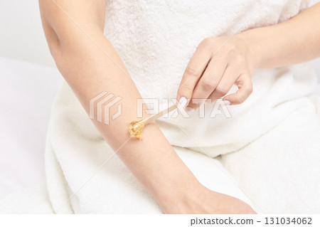 Caucasian female adult applying wax on arm for hair removal process at home 131034062