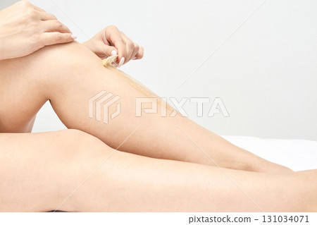 Female hair removal process on legs: close-up of waxing technique on caucasian 131034071