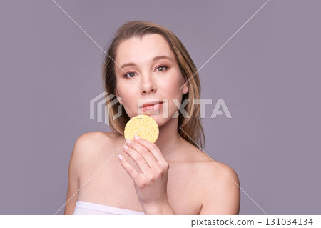 Caucasian female adult holding facial sponge for skincare routine on light 131034134