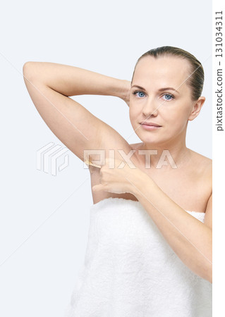 Caucasian female adult applying deodorant in towel with hair pulled back Caucasian female adult applying deodorant in towel with hair pulled back 131034311