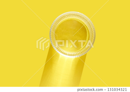 Close-up of translucent plastic film roll against bright yellow background 131034321
