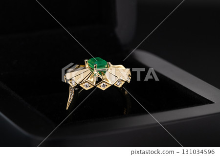 A gold and emerald ring with diamonds in the center A gold and emerald ring with diamonds in the center 131034596