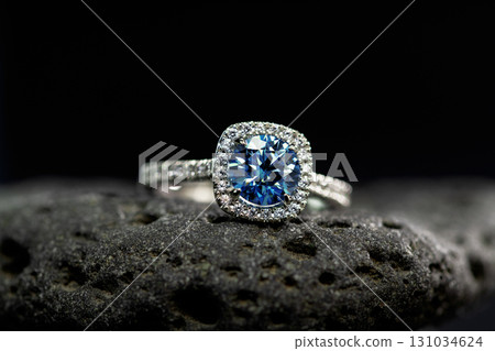 A blue sapphire diamond ring with a white band sits on a rock 131034624