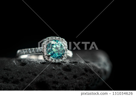 A blue diamond ring sits on a rock 131034626