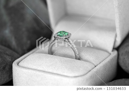 A green emerald diamond ring is in a white box 131034633
