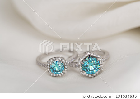 Two blue diamond paraiba tourmaline rings are displayed on a white cloth 131034639