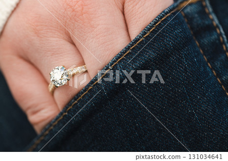 A woman is wearing a gold and diamond ring on her finger A woman is wearing a gold and diamond ring on her finger 131034641