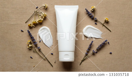 Pure white cosmetic cream tube surrounded by delicate lavender and chamomile flowers on natural linen fabric 131035718