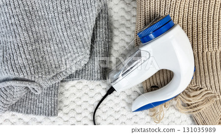 A lint remover against a warm cozy sweaters with bobbles. Preparing wardrobe and caring for clothes, clothing care and maintenance, fall and winter fashion and garment preparation A lint remover against a warm cozy sweaters with bobbles. Preparing wardrobe and caring for clothes, clothing care and maintenance, fall and winter fashion and garment preparation 131035989