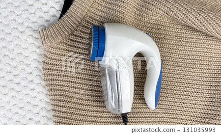 A lint remover against a warm cozy sweater with bobbles. Preparing wardrobe and caring for clothes, clothing care and maintenance, fall and winter fashion and garment preparation 131035993
