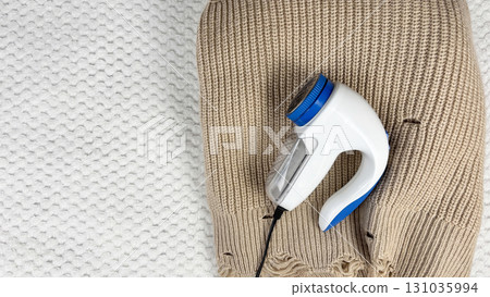 A lint remover against a warm cozy sweater with bobbles. Preparing wardrobe and caring for clothes, clothing care and maintenance, fall and winter fashion and garment preparation A lint remover against a warm cozy sweater with bobbles. Preparing wardrobe and caring for clothes, clothing care and maintenance, fall and winter fashion and garment preparation 131035994