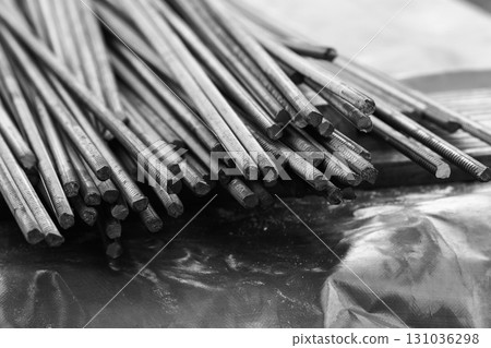 Steel reinforcement bars are piled outdoor. Black and white photo Steel reinforcement bars are piled outdoor. Black and white photo 131036298