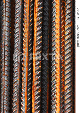 Detailed vertical macro photo of steel reinforcement bars featuring orange rust 131036300