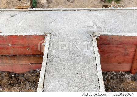 A concrete foundation is being formed between red wooden boards 131036304