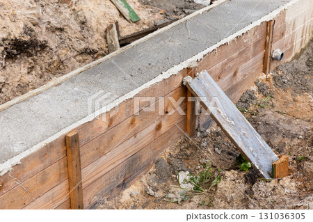A wooden formwork wall borders a freshly poured concrete slab A wooden formwork wall borders a freshly poured concrete slab 131036305