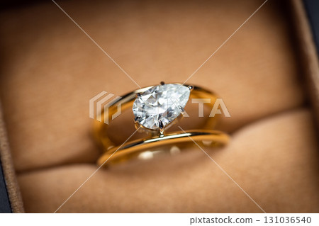 A gold and diamond ring with a pear cut diamond in the center 131036540