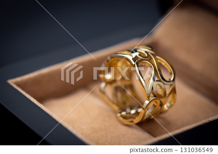 A gold ring with a design on it sits in a box A gold ring with a design on it sits in a box 131036549