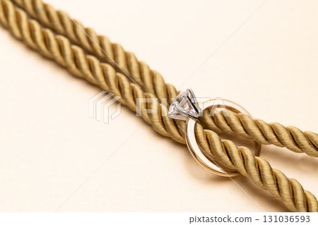 A gold rope with a diamond ring on it 131036593