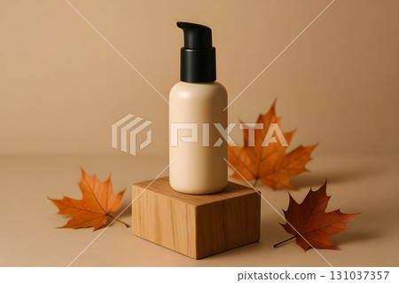 A beige lotion bottle with a pump top stands on a wooden block, accented by autumn leaves. A beige lotion bottle with a pump top stands on a wooden block, accented by autumn leaves. 131037357