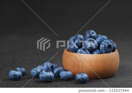 Fresh ripe blueberries in wooden bowl on dark gray stone background closeup macro healthy food Fresh ripe blueberries in wooden bowl on dark gray stone background closeup macro healthy food 131037444