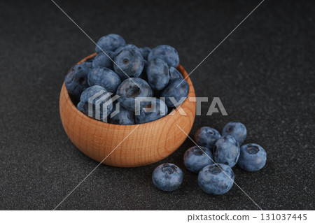 Fresh ripe blueberries in wooden bowl on dark gray stone background closeup macro healthy food Fresh ripe blueberries in wooden bowl on dark gray stone background closeup macro healthy food 131037445