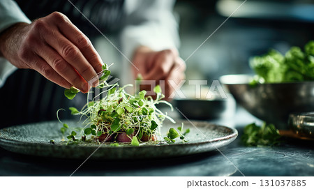Chef garnishing dish with microgreens in kitchen Chef garnishing dish with microgreens in kitchen 131037885