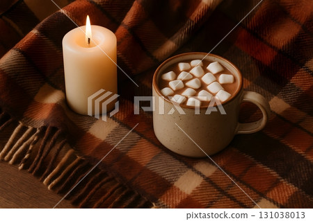 Cozy scene with a cup of hot chocolate topped with marshmallows on a plaid blanket 131038013