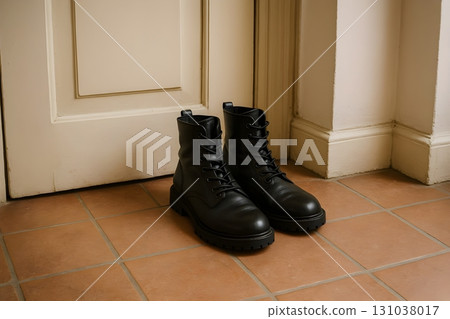 Black leather lace-ups by a closed door, set against terracotta tiles. 131038017