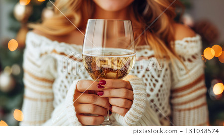 Woman holding a glass of sparkling wine, celebrating in a cozy holiday atmosphere with festive lights 131038574