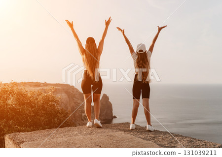Two Women with Arms Raised in Triumph on a Cliffside 131039211