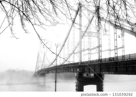 A solitary bridge emerges from the ethereal embrace of mist. 131039292