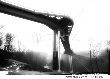 Black and white photo of a steel bridge over a river in fog 131039298