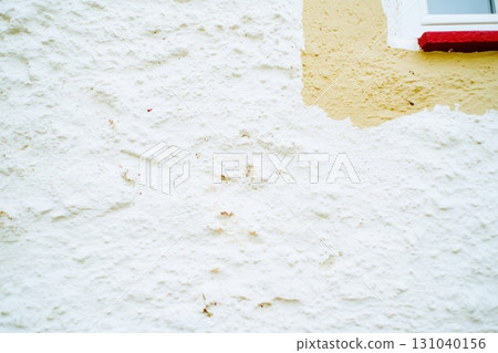 Textured wall with a patch of yellow paint near a window 131040156