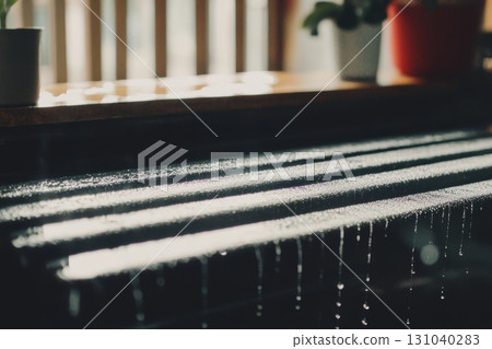 Raindrops glisten on a wooden surface with sunlight pouring through 131040283